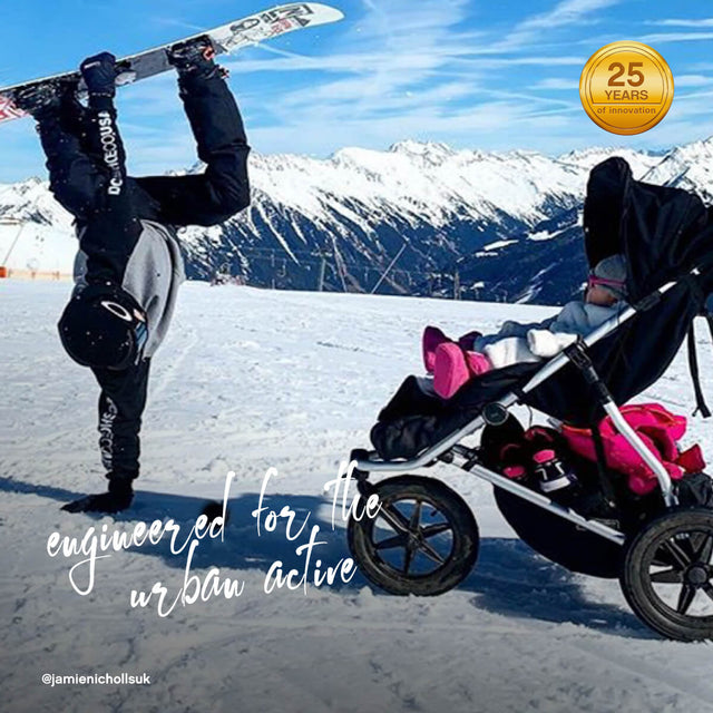 active family visiting snowy mountains as toddler keeps warm riding in mountain buggy urban jungle all-terrain with sleeping bag